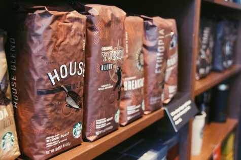 The glossy new bags of fresh coffee grinds sit proudly on a shelf in the sunlight.
