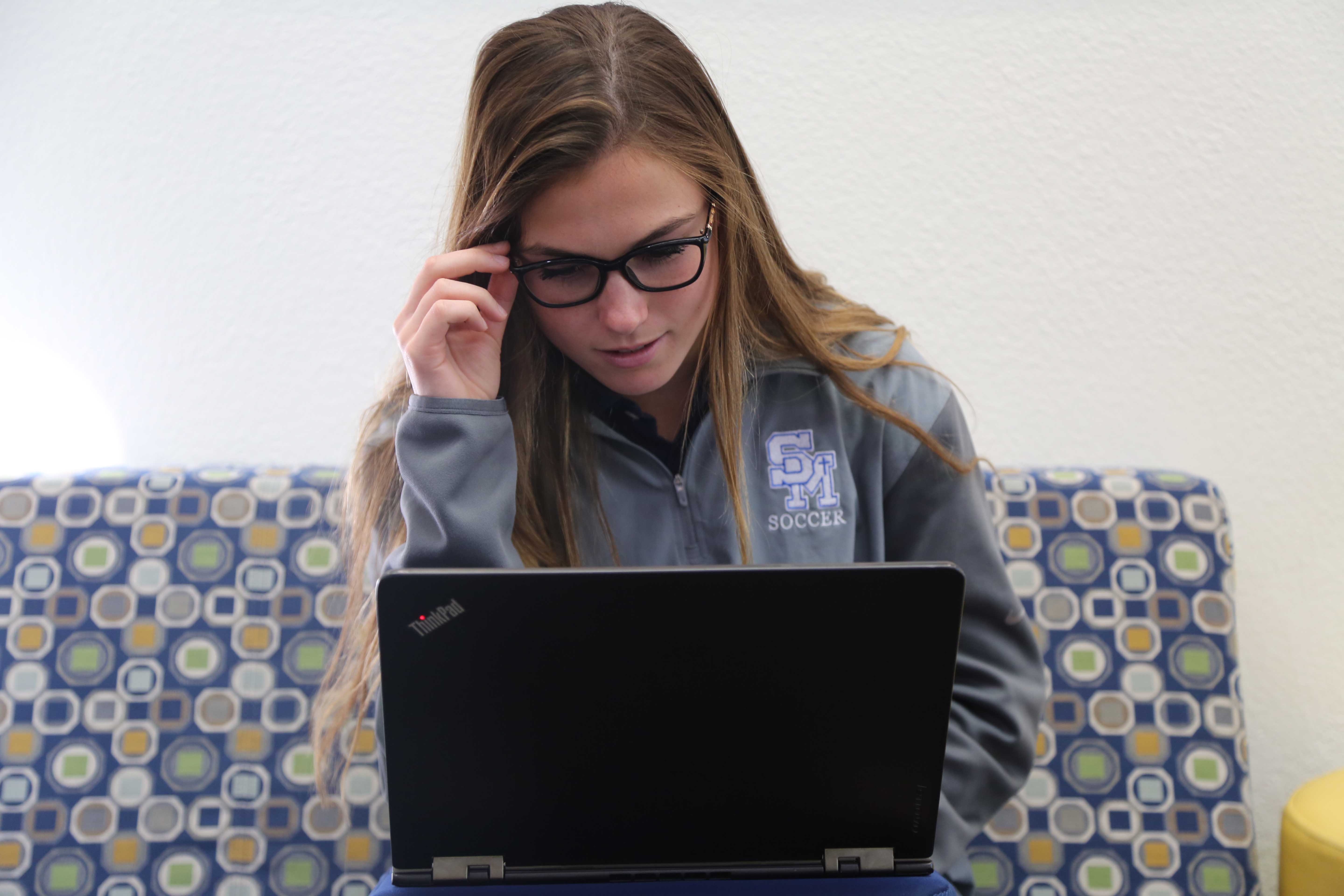 Junior Madison Louderback looks at her Lenova Yoga tablet with a new view and new prescription glasses.