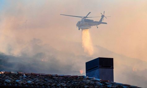 A helicopter rushes to help contain the fire by dropping water. (Photo by Orange County Register)