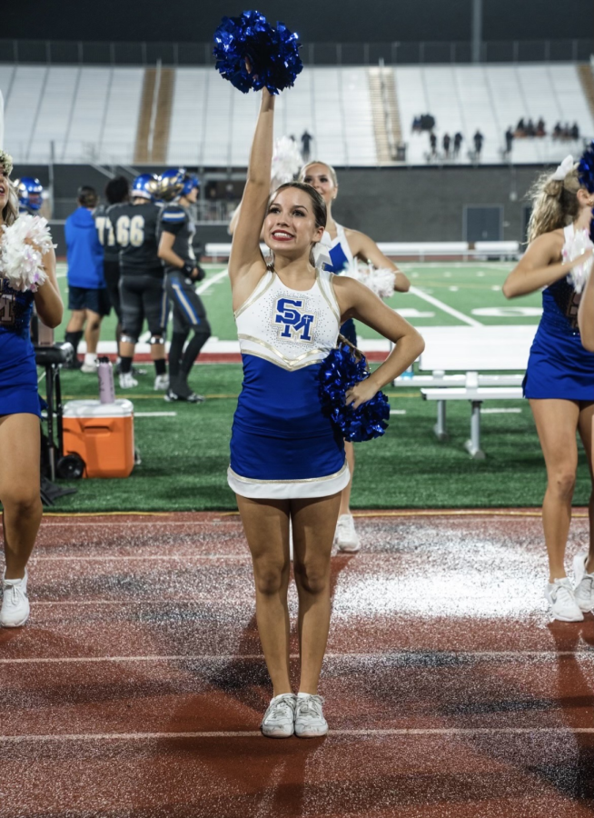 Cheering on the sidelines at a football game, Kacer applies what her coaches have taught her.